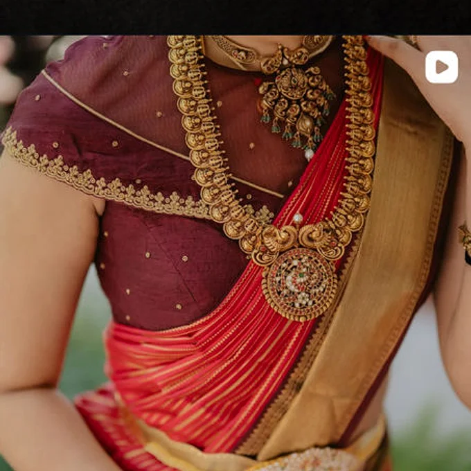 A maroon blouse and red silk saree worn with choker, haram and pearls