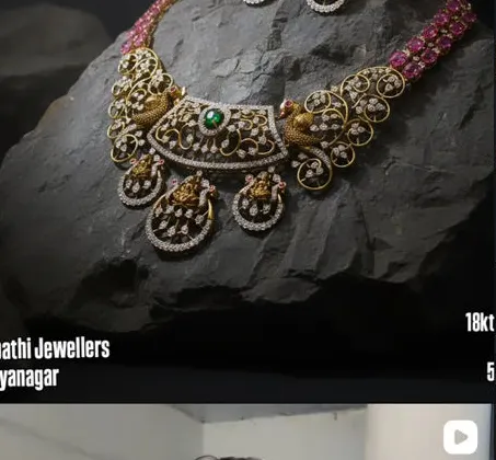 A diamond and emerald necklace photographed on black rock, from their 18 karat line
